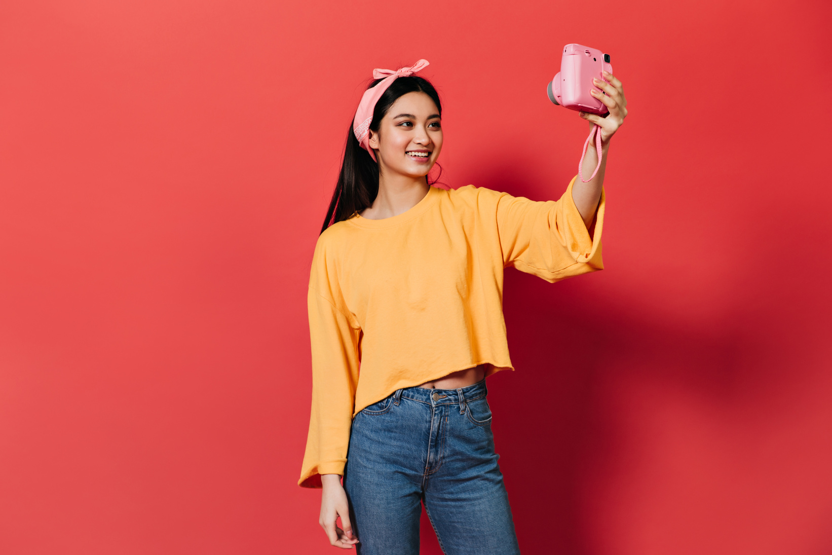 Cute Brunette Girl Smiles and Makes Selfie on Pink Camera