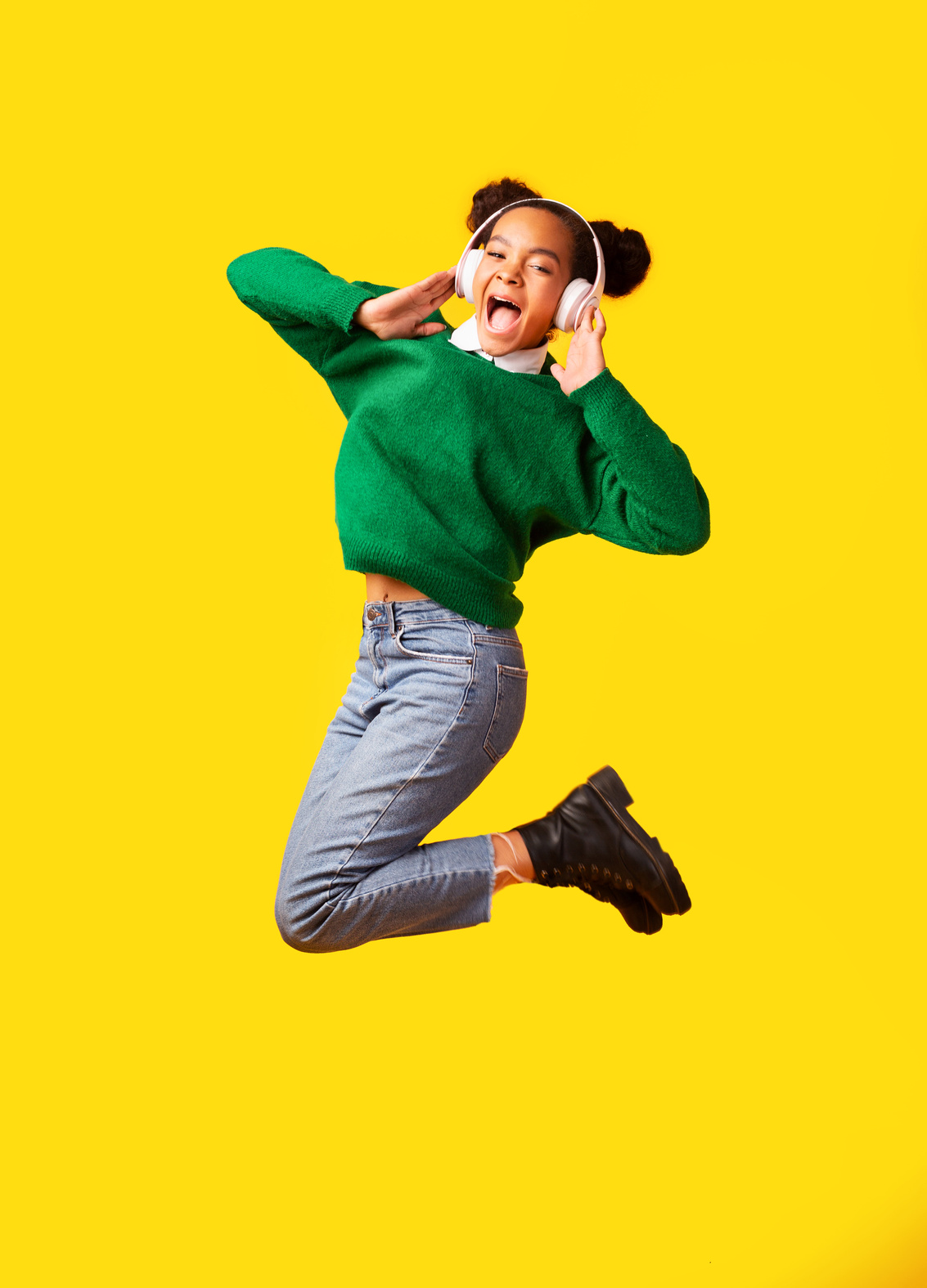 Excited afro teen jumping over studio background in headset